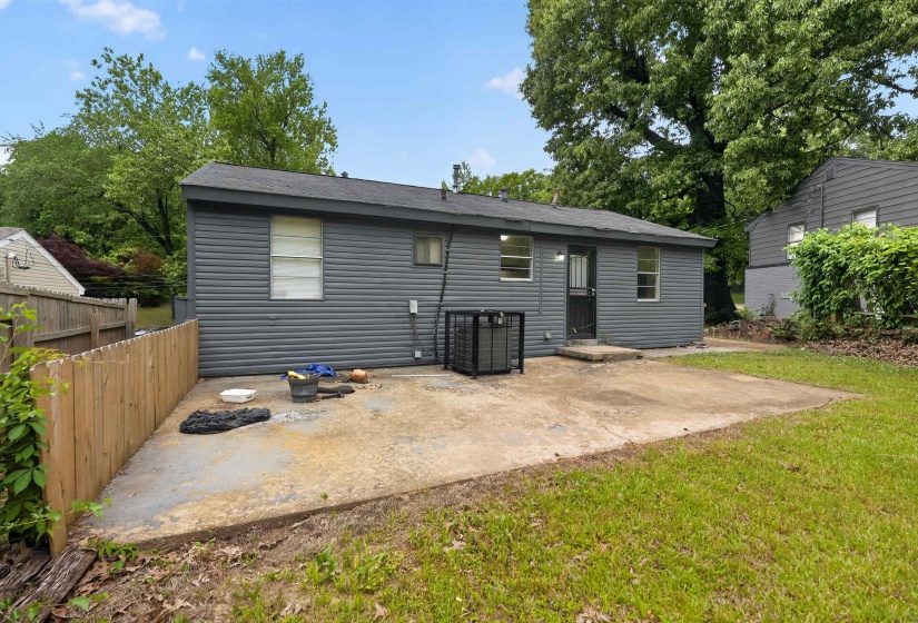 Rear exterior featuring gray horizontal siding, a concrete patio, and a wood privacy fence