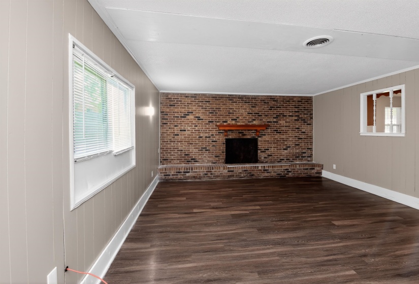 Spacious interior with wood-finish flooring and a brick-surround fireplace