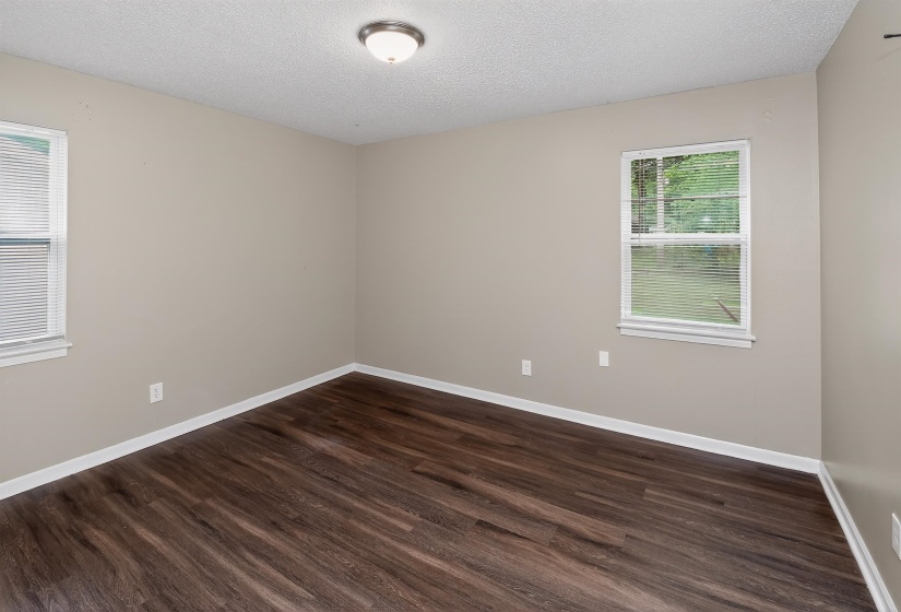 Spacious room featuring wood-finish flooring, neutral-toned walls, and white trim