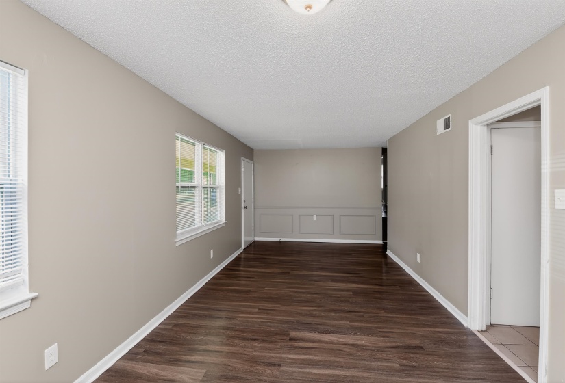 Expansive room featuring wood-finish flooring, neutral wall paint, white trim, and multiple windows with blinds