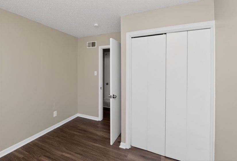 Room featuring wood-finish flooring, neutral wall color, white baseboards, and a white bi-fold closet