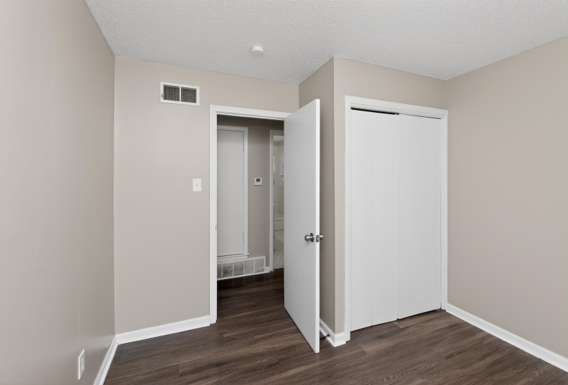 Interior room featuring neutral wall paint, wood-finish flooring, white baseboards, and a white bi-fold closet door