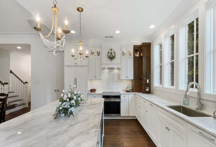 Gourmet kitchen featuring a substantial island with a stone countertop, white shaker cabinetry, stainless steel appliances, a white tile backsplash, and dark wood-finish flooring