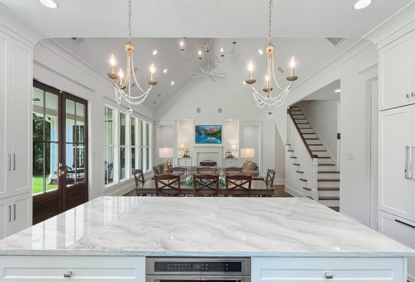 Kitchen island with a polished countertop, integrated appliances, and white cabinetry