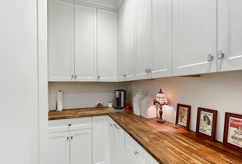 Kitchen featuring extensive white shaker cabinetry, wood-finish countertops, and an integrated backsplash