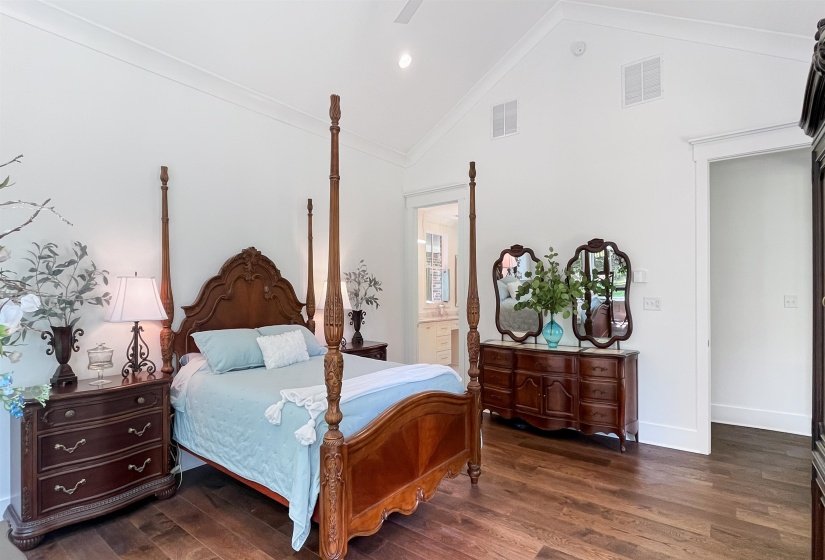 Vaulted ceiling bedroom featuring wood-finish flooring