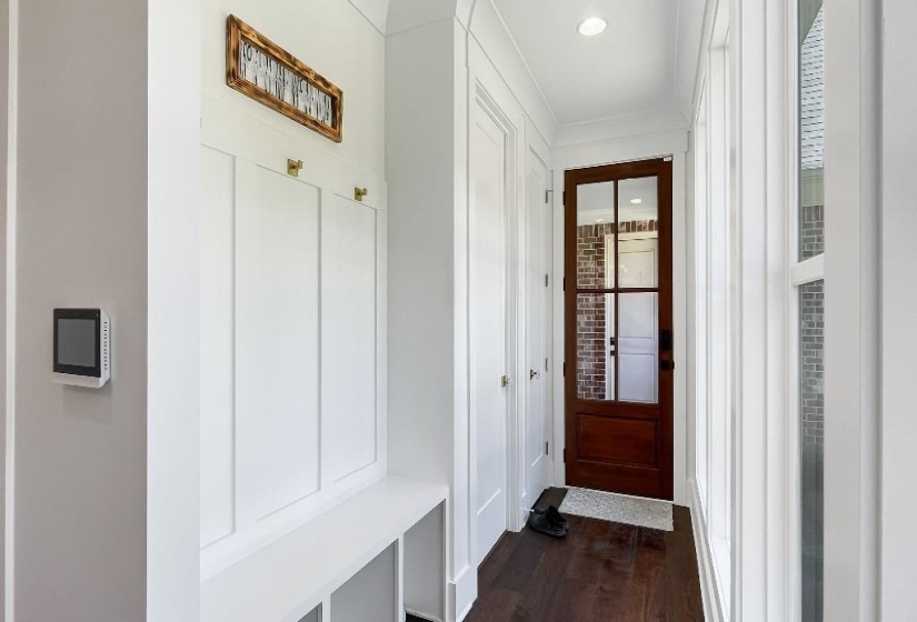 Entryway mudroom featuring built-in bench storage, white board-and-batten detailing, and dark wood-finish flooring