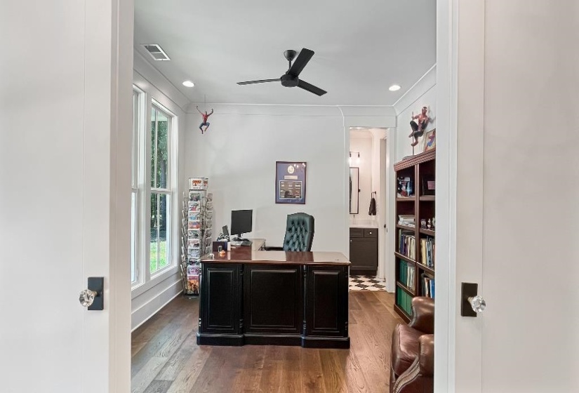 Spacious room featuring wood-finish flooring, white walls, multiple windows, a ceiling fan, and recessed lighting