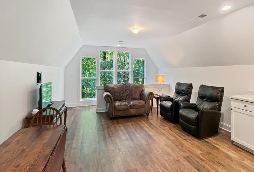 Spacious bonus room featuring wood-finish flooring, multiple windows, recessed lighting, and a built-in cabinet with a light-colored countertop
