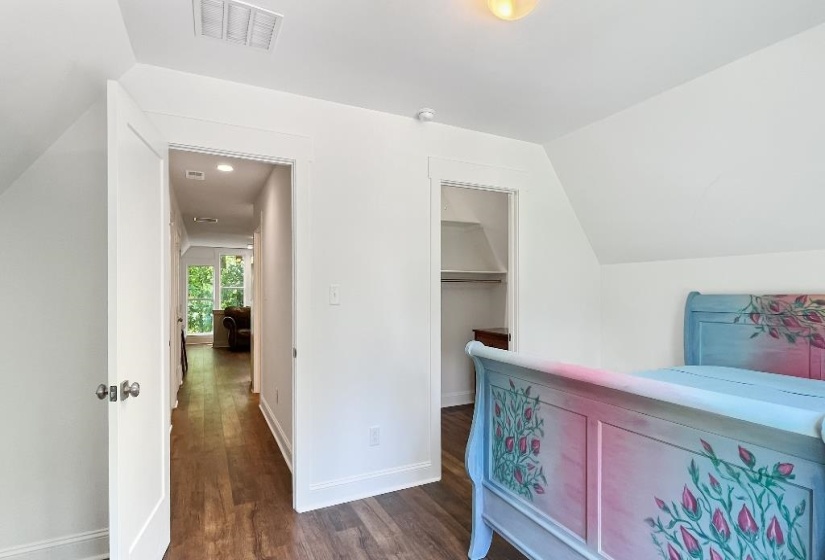 Attic room featuring wood-finish flooring, white walls, and an open closet space
