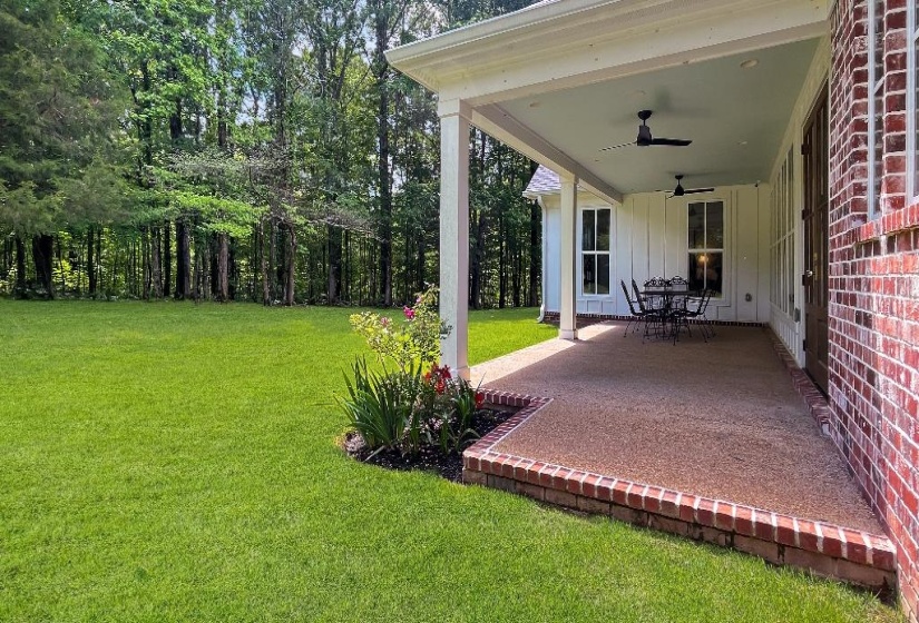 Expansive covered patio with exposed aggregate flooring and brick border