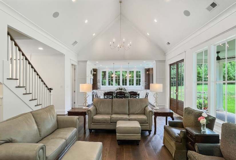 Spacious living area featuring a vaulted ceiling, recessed lighting, and dark wood-finish flooring