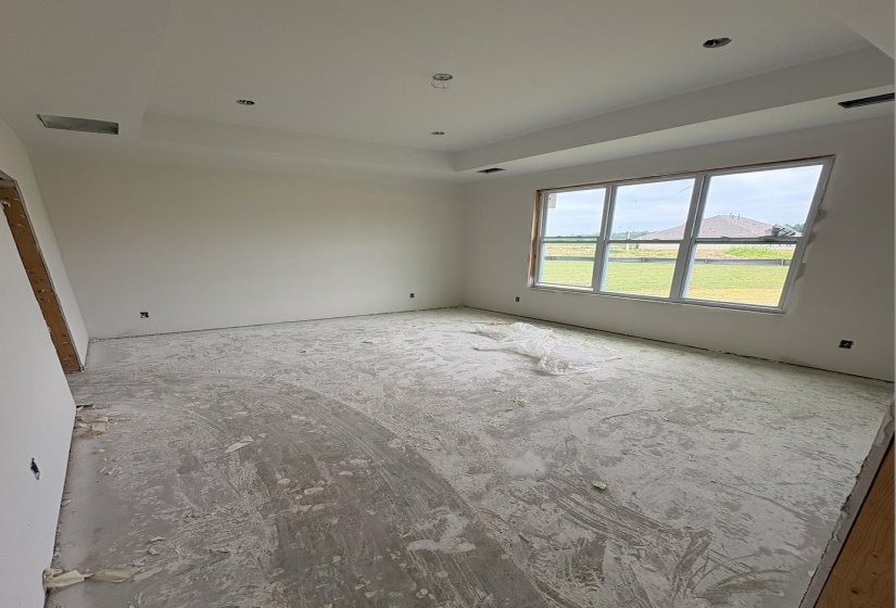 Spacious room featuring a tray ceiling with recessed lighting, large multi-pane window, and primed walls