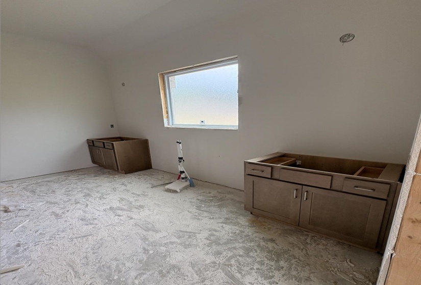 Light-filled room featuring a single window and two installed vanity cabinets