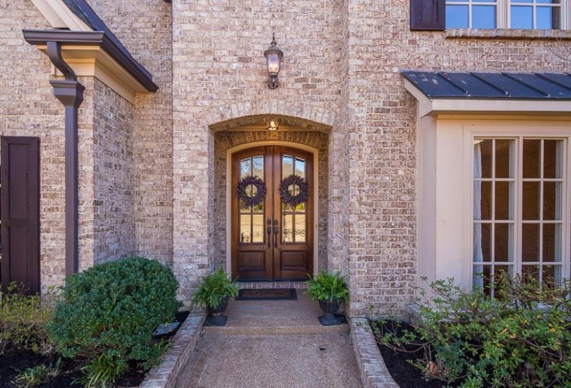 Brick facade featuring an arched entryway with double wooden doors