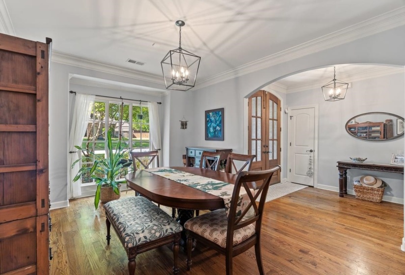 Hardwood flooring throughout featuring a large arched entryway, and crown molding.  Updated light fixture