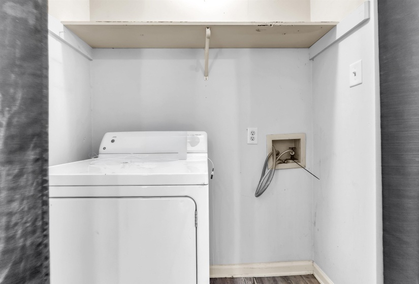 Dedicated laundry alcove with wood-finish flooring, light gray walls, built-in shelving, and utility hookups
