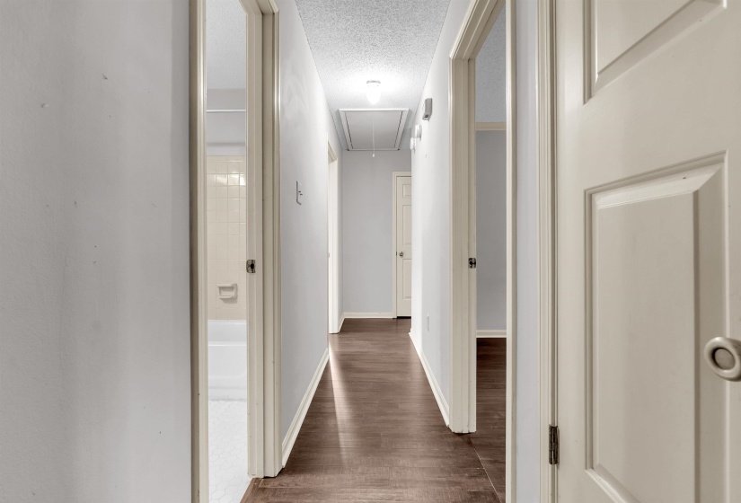 Hallway featuring wood-finish flooring, light grey wall paint, and white trim