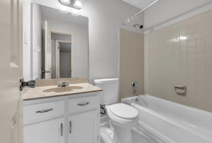 Full bathroom with a white vanity and integrated sink, a rectangular mirror, and a combination shower/tub