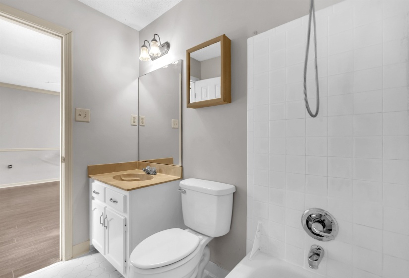 Bathroom featuring a white vanity with built-in sink, a wall-mounted mirror, and a tiled shower/tub combination with chrome fixtures