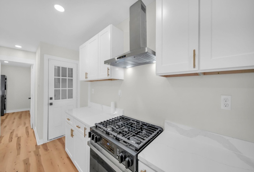 Kitchen featuring range with gas cooktop, white cabinetry, range hood, recessed lighting, and light stone countertops