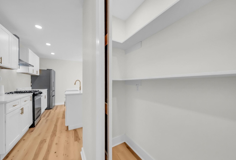 Kitchen with white cabinetry, recessed lighting, range with gas cooktop, light wood finished floors, and freestanding refrigerator