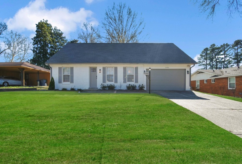 Ranch-style house featuring a front lawn, driveway, and an attached garage