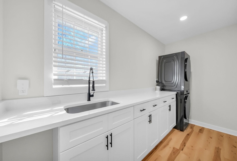 Washroom with stacked washer / dryer, light wood finished floors, cabinet space, and recessed lighting