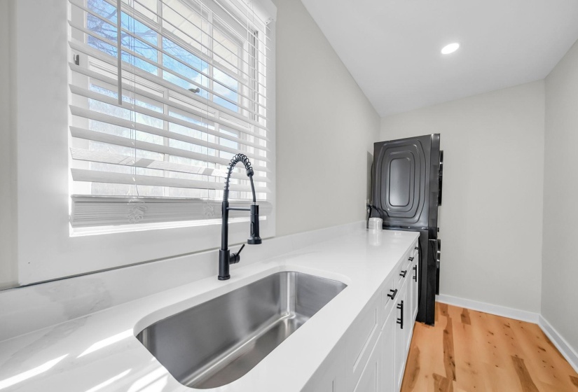 Kitchen with white cabinetry, light wood-type flooring, light stone counters, and recessed lighting