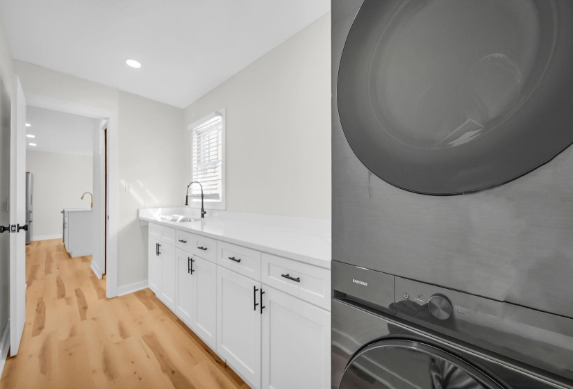 Laundry room featuring light wood finished floors, recessed lighting, stacked washing machine and dryer, and cabinet space