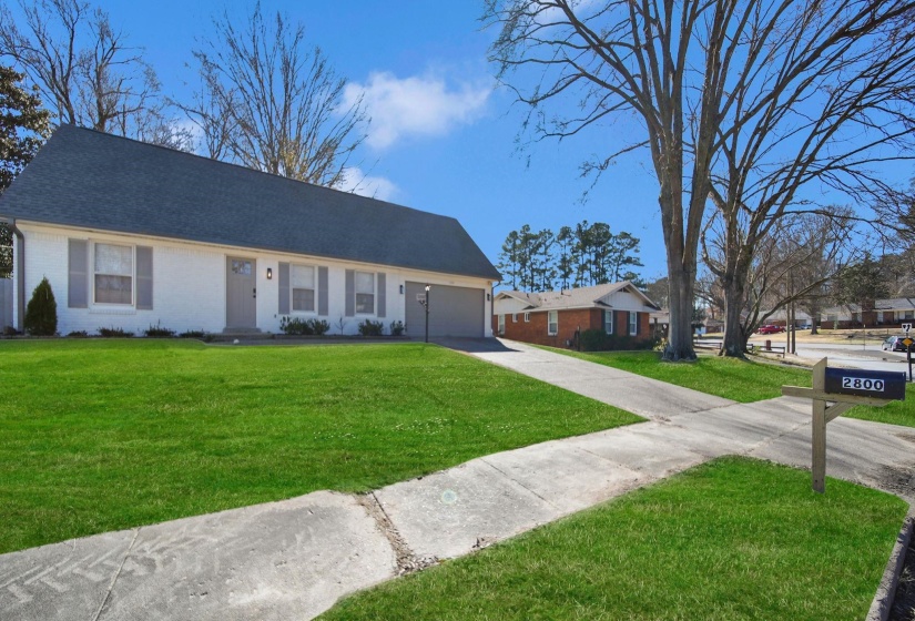 Ranch-style home featuring brick siding, driveway, a front lawn, and a garage