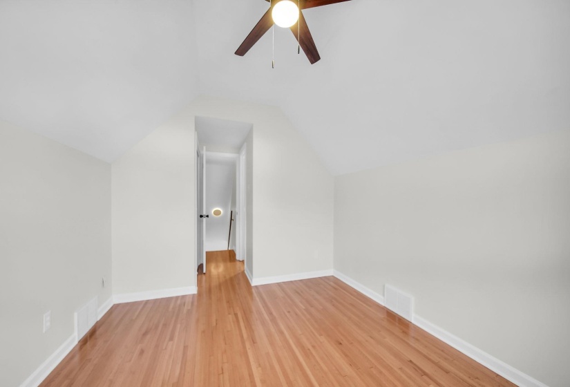 Additional living space featuring lofted ceiling, light wood-style floors, and a ceiling fan