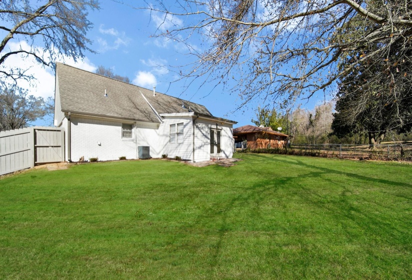 Back of house featuring a fenced backyard, brick siding, a gate, and a shingled roof
