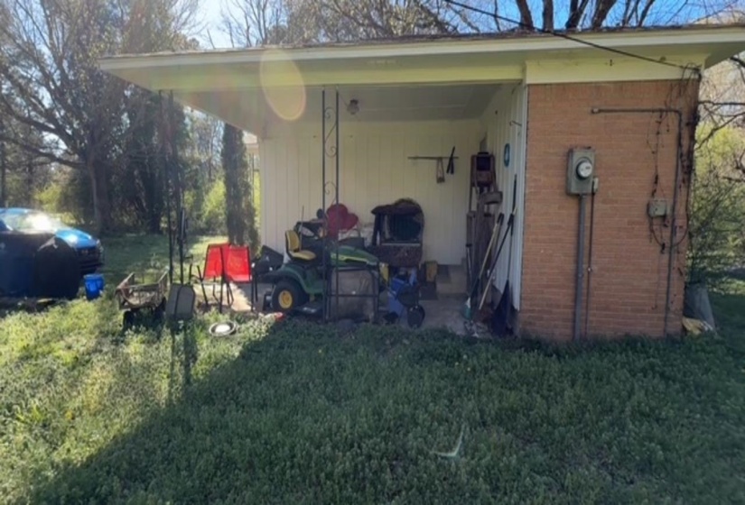 Covered outdoor area featuring a concrete pad, brick exterior wall, and white siding