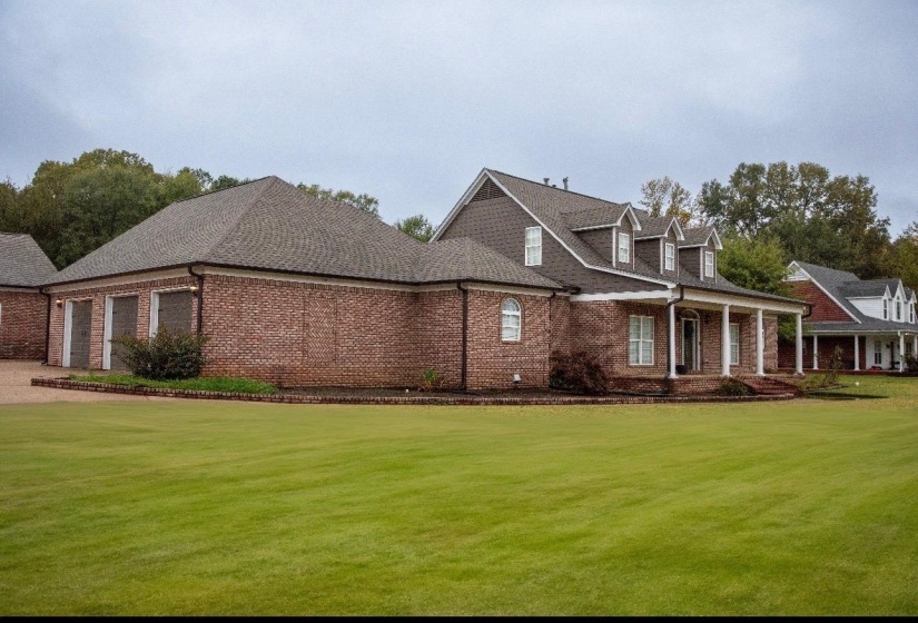 Brick exterior with a prominent front porch supported by white columns, multiple dormer windows, and a three-car garage