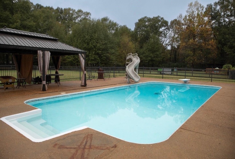 Rectangular swimming pool featuring a built-in slide, diving board, and integrated steps