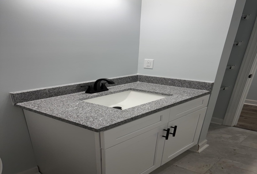 Bathroom vanity featuring a speckled countertop, integrated sink, and matte black faucet