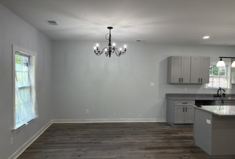 Open-concept living space featuring wood-finish flooring and a contemporary chandelier
