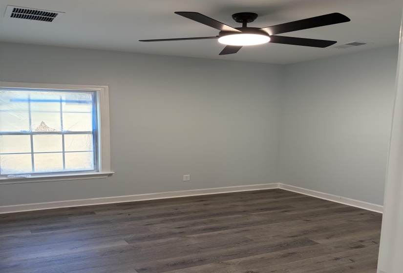 Room featuring a contemporary ceiling fan with integrated lighting, wood-finish flooring, light gray wall paint, white baseboards, and a window with white trim