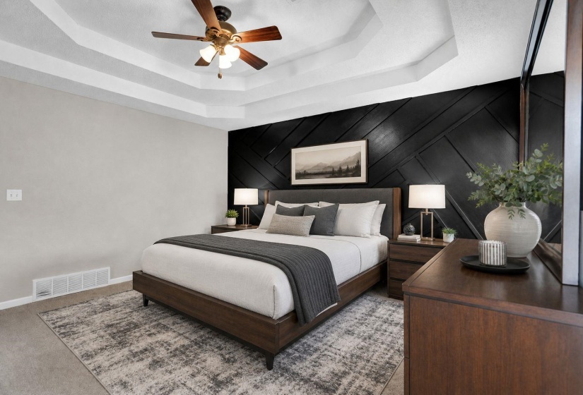 Carpeted bedroom with an accent wall, ceiling fan, wooden walls, and a raised ceiling