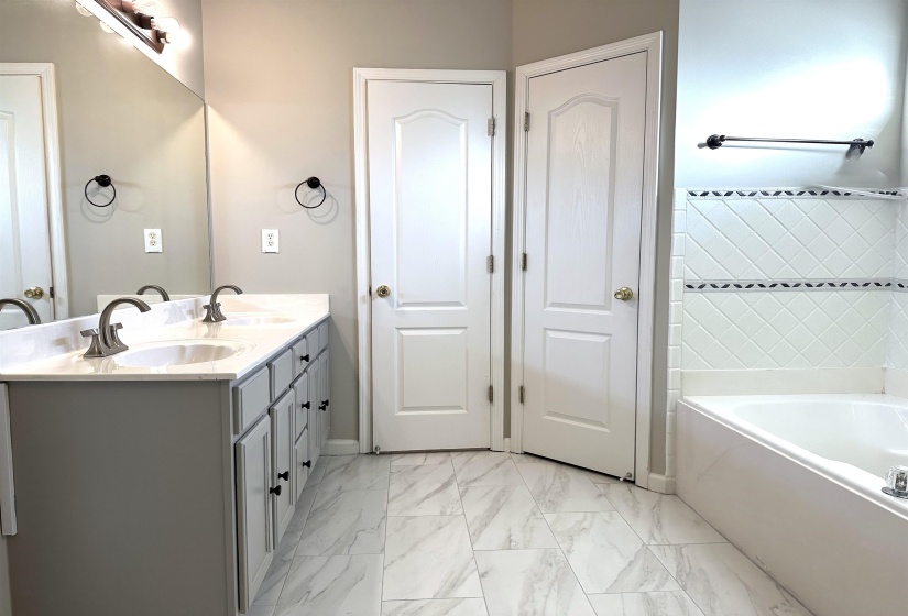 Bathroom featuring double vanity, a garden tub, and light marble finish floors