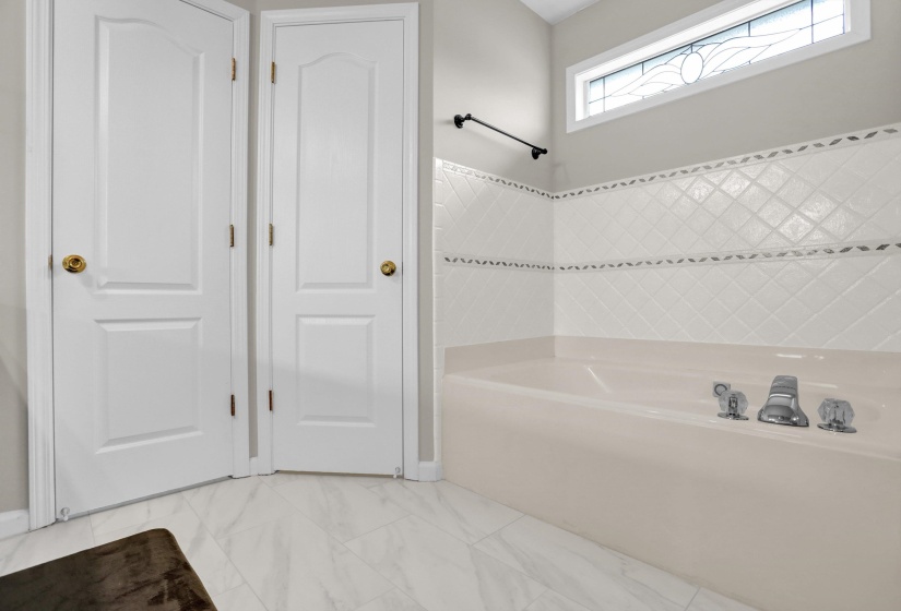 Full bath featuring a garden tub and light marble finish floors