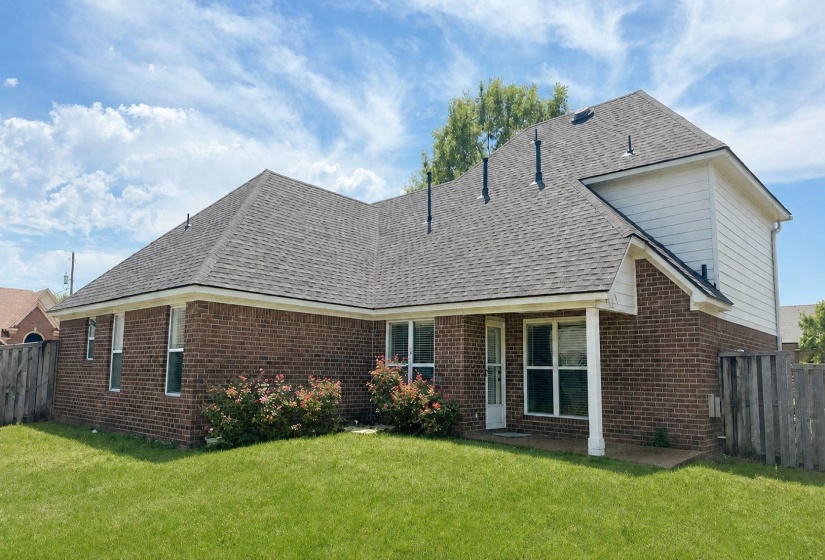 Rear view of property featuring a fenced backyard, a patio, brick siding, and roof with shingles