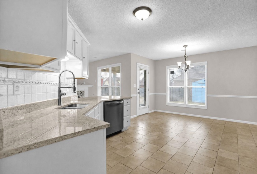 Kitchen with light stone counters, white cabinetry, freestanding refrigerator, a textured ceiling, and a chandelier