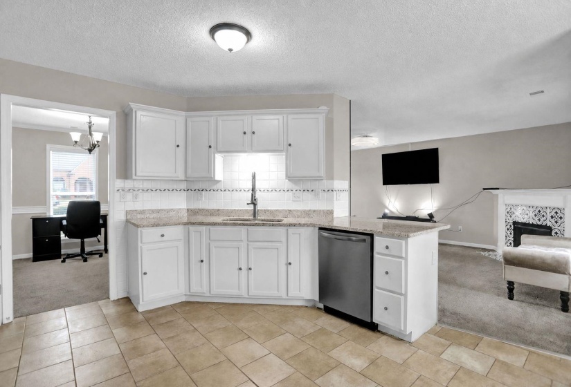Kitchen featuring light carpet, an office area, white cabinets, and a textured ceiling