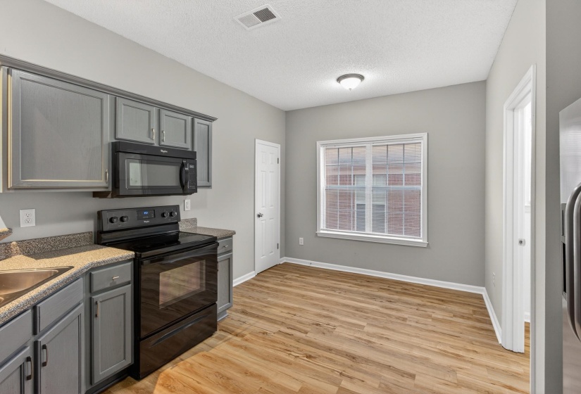 Kitchen featuring gray cabinetry, black appliances, laminate countertops, and wood-finish flooring
