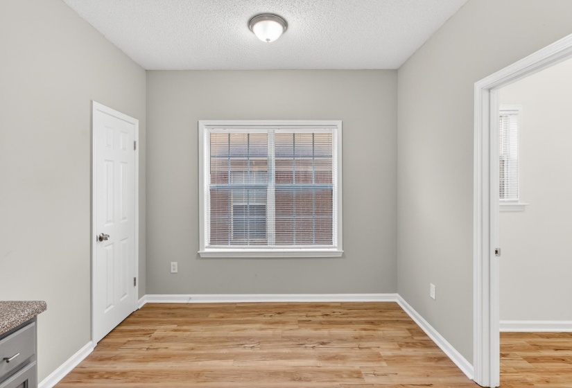 Room with wood-finish flooring, light grey walls, and white trim