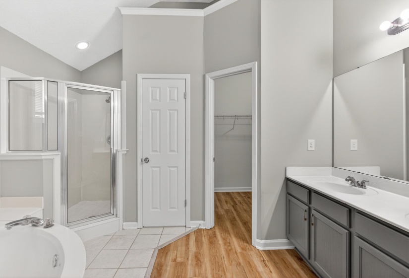 Bathroom featuring a glass-enclosed shower, a separate soaking tub, and a dual vanity with a large mirror