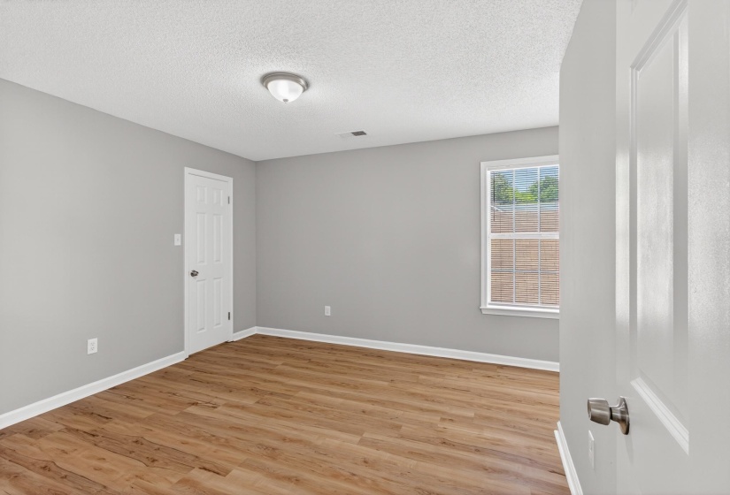 Room featuring wood-finish flooring, light gray wall paint, and white trim