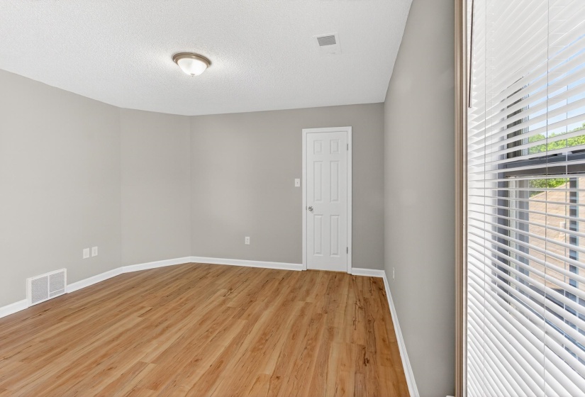 Spacious room featuring wood-finish flooring, light gray walls, and white trim